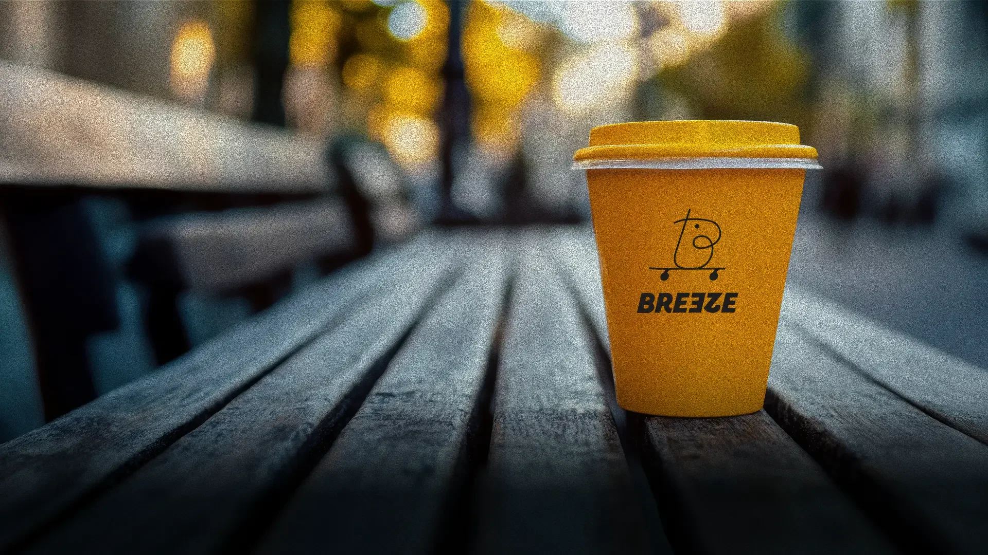 A yellow Bre3ze coffee cup on a park bench
